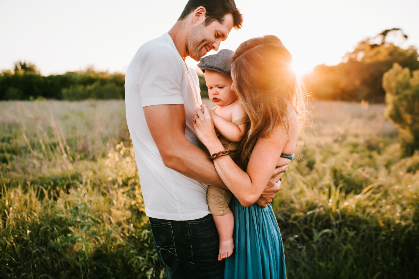 Nanda & Associate Lawyers Canada - Husband and wife hugging and holding baby outside in a grass field