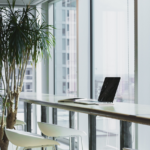 Nanda & Associate Lawyers Canada - Laptop on desk with a white stool in a glass office overlooking the city