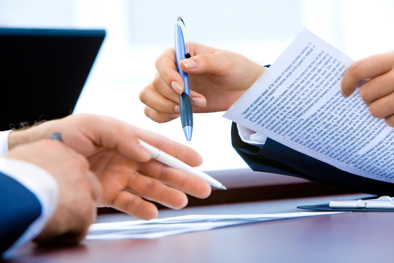 Man and woman in meeting room with pens and documents in hand