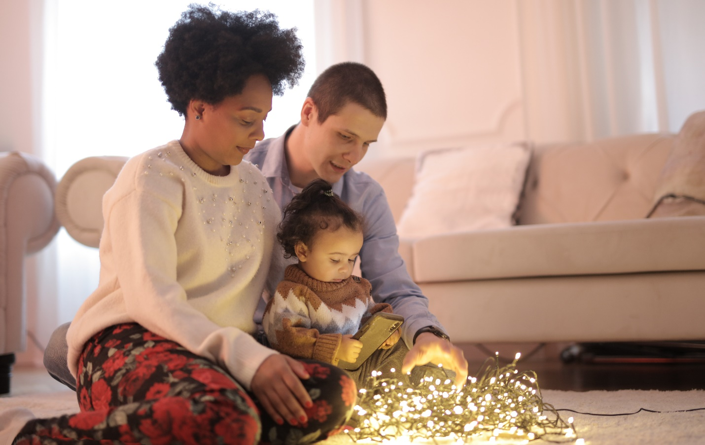 A couple sitting on the floor with a kid.