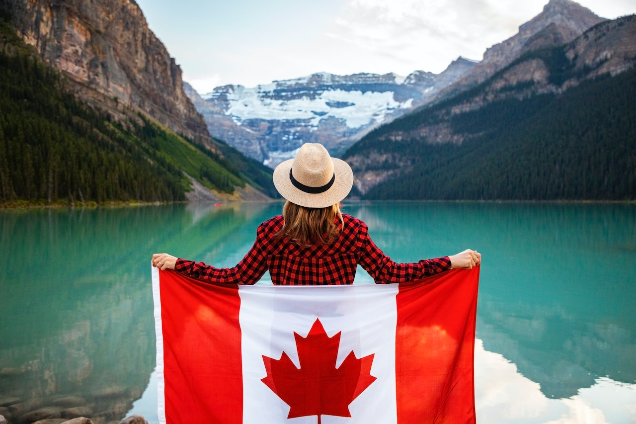 Nanda & Associate Lawyers Canada - A person holding the Canadian flag near a body of water