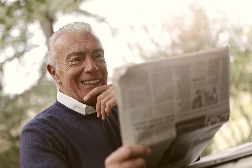 Nanda & Associate Lawyers Canada - A senior citizen smiling while reading the newspaper
