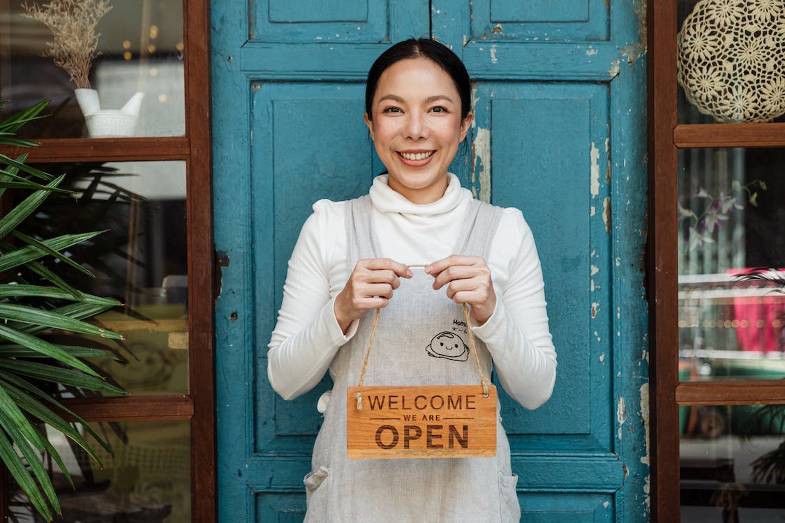 Nanda & Associate Lawyers Canada - small business owner holding an open sign for her business