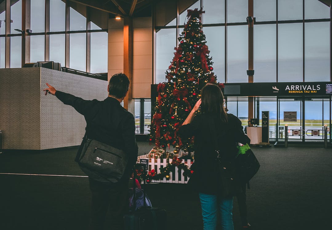 Nanda & Associate Lawyers Canada - Two people standing in front of a Christmas tree at an airport